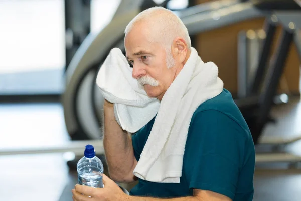 Anciano cansado en un gimnasio con toalla — Foto de Stock