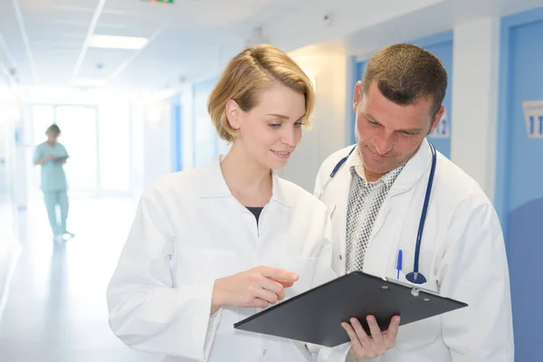 Dva lékaři s schránky na chodbě nemocnice — Stock fotografie