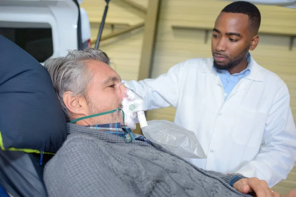 Male patient on stretcher wearing oxygen mask — Stock Photo, Image
