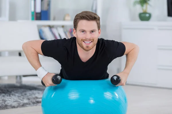 Schöner Mann macht Sit-ups im hellen Wohnzimmer — Stockfoto