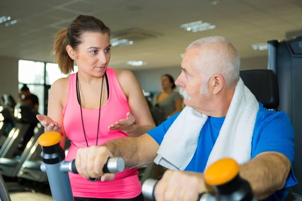 Starší muž trénink s trenérem ve fitness studiu — Stock fotografie