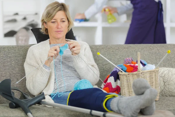 Femme blessée gaie tricot sur le canapé — Photo