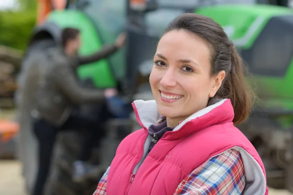 Mooie vrouw poseren voor een tractor — Stockfoto