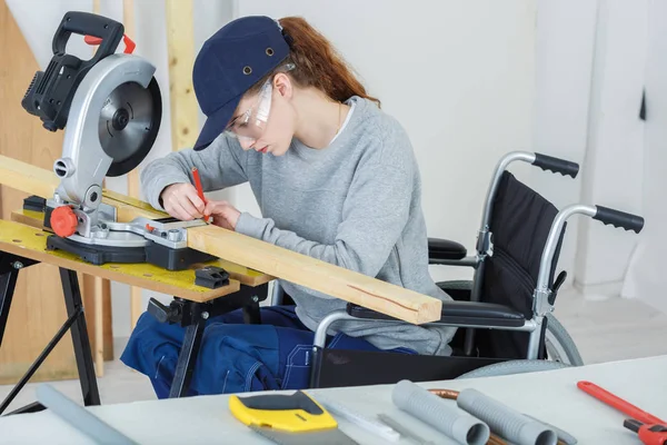 Женщина-инвалид в инвалидной коляске в мастерской плотников — стоковое фото