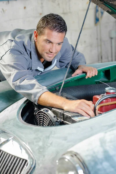 Jeune mécanicien vérifiant un moteur — Photo