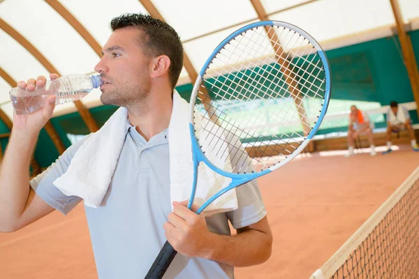 Uomo sul campo da tennis a bere qualcosa — Foto Stock