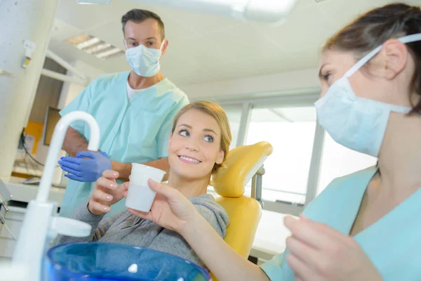 Mulher sorrindo está tomando um copo de água em dentistas — Fotografia de Stock