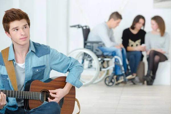 Young man playing a guitar in a school — Stock Photo, Image