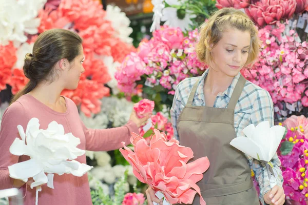 Florista heerful mostrando cliente feminino um monte de flores — Fotografia de Stock