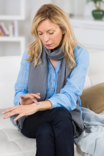 Senior aantrekkelijke vrouw verspreid crème op haar voorarm — Stockfoto