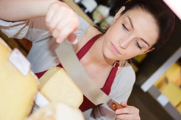 Vendedora corte de queijo e feminino — Fotografia de Stock