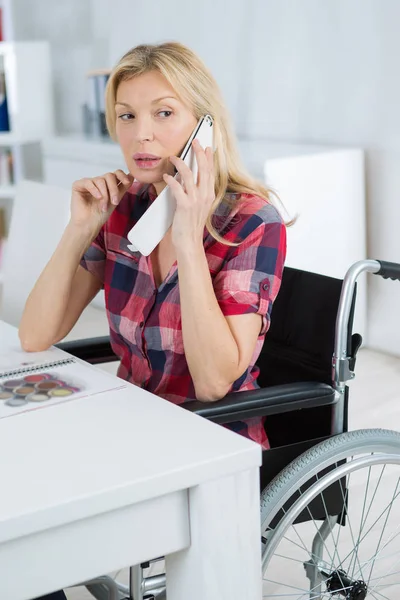 Deficiente senhora sentou-se na mesa no telefone — Fotografia de Stock
