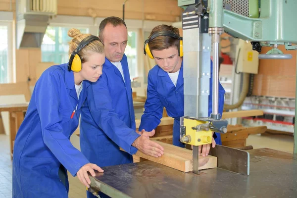 Estudantes assistindo carpinteiro usar serra de banco — Fotografia de Stock
