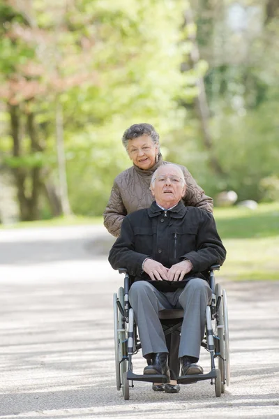 高齢者の女性が車椅子の人を押す — ストック写真