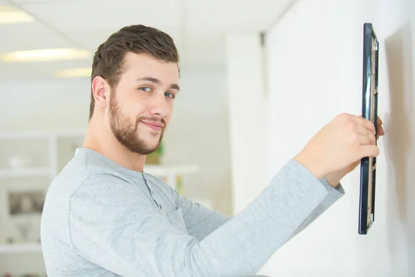 Man putting picture frame onto wall — Stock Photo, Image