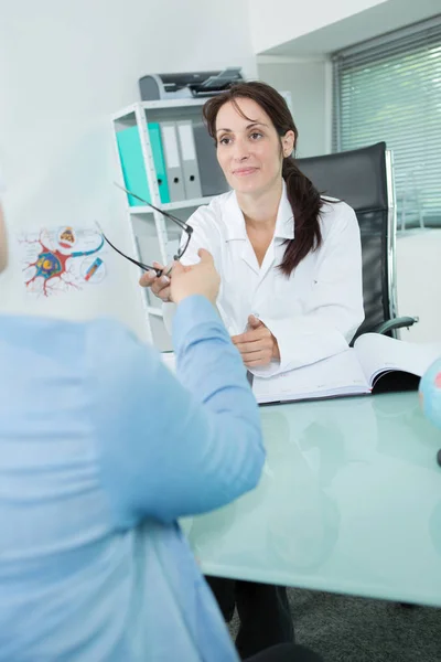 Vrouwelijke opticien bril frames met klant — Stockfoto