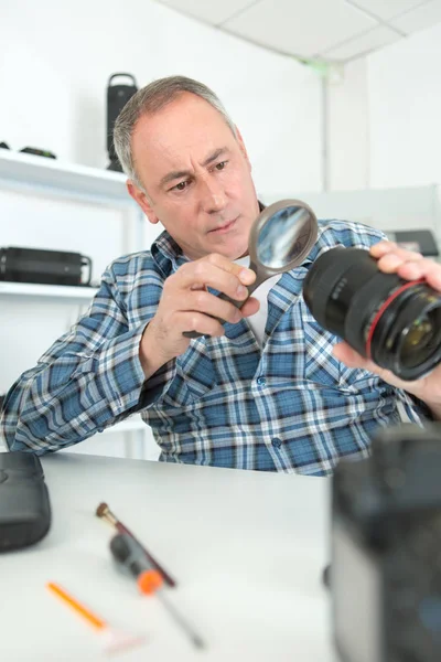 Мужчина смотрит на сломанный фотообъектив — стоковое фото