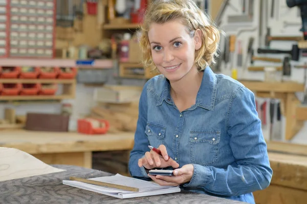 Portret van een vrouw in werkplaats, met behulp van de rekenmachine — Stockfoto