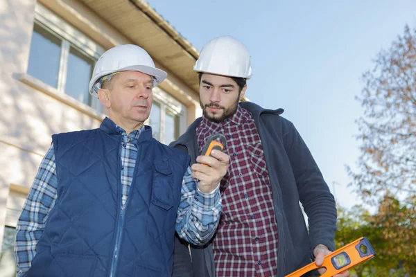 Dos trabajadores de la construcción tomando medidas — Foto de Stock