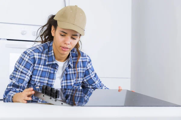 若い repairwoman の台所で電磁調理器をインストールします。 — ストック写真