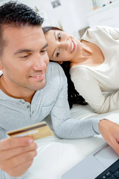 Couple using laptop and holding payment card — Stock Photo, Image