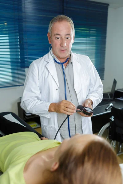 Médico sênior tomando pressão arterial das mulheres em casa — Fotografia de Stock