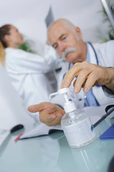 Médico sênior desinfectando suas mãos — Fotografia de Stock