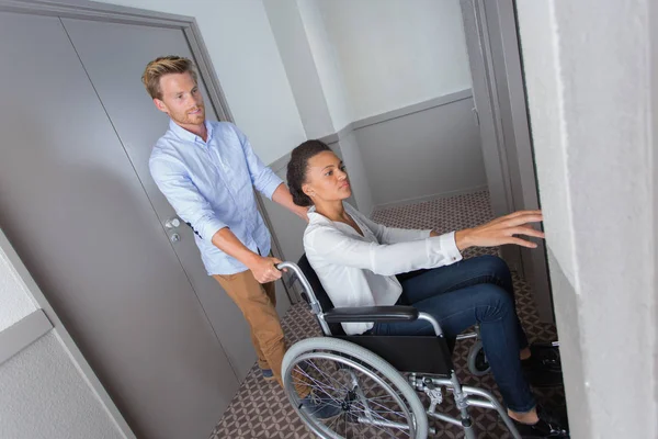 Behinderte Frau im Rollstuhl von ihrem Freund geschoben — Stockfoto