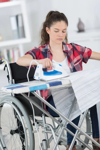 Ragazza sulla sedia a rotelle vestiti stiratura — Foto Stock