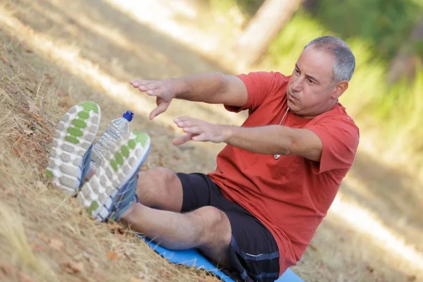 Knappe senior man rekken en opwarmen voordat joggen — Stockfoto