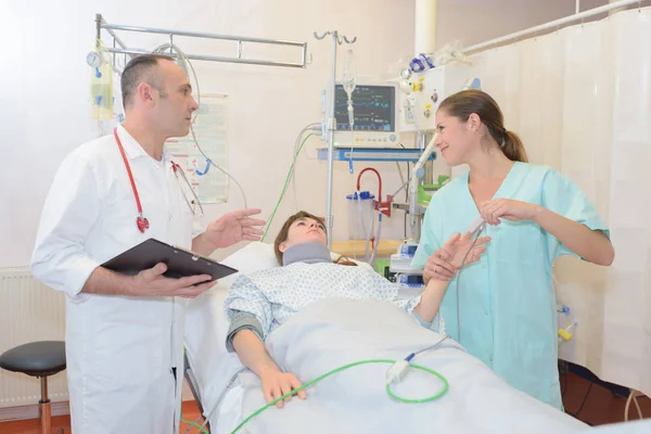 Team sjuksköterska läkare med patienten i sjukhussäng — Stockfoto