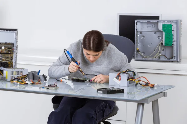Vrouw die werkt op computer met soldeerbout — Stockfoto