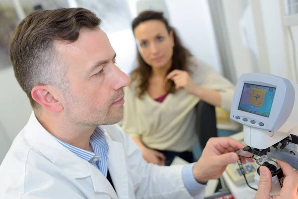 El médico comprueba los ojos de un paciente usando el dispositivo oftálmico — Foto de Stock