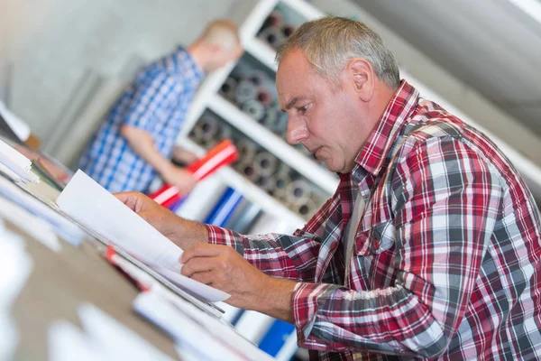 Senior aannemer bij balie doen papierwerk — Stockfoto