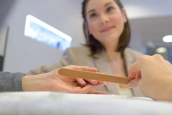 Manicure que faz um arquivamento de prego em um salão — Fotografia de Stock