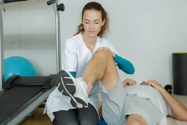 Fisioterapeuta trabajando en la pierna de un hombre — Foto de Stock