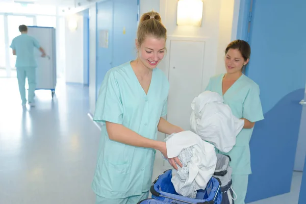 Infirmières auxiliaires ramassant la blanchisserie — Photo