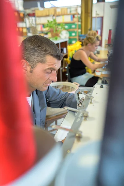 Чоловік на роботі використовує швейну машину — стокове фото
