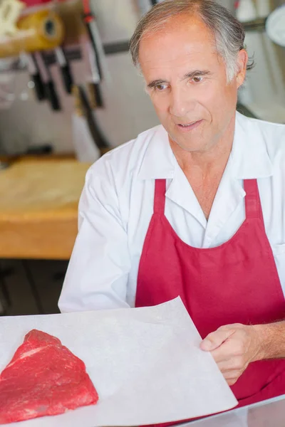 Açougueiro apresentando corte de carne bovina ao cliente — Fotografia de Stock