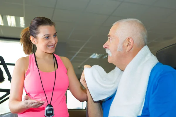 Happy female trainer with senior in fitness studio — Stock Photo, Image