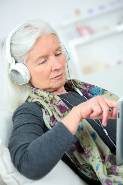 Idős nő a fülhallgató csatlakozik a tabletta — Stock Fotó