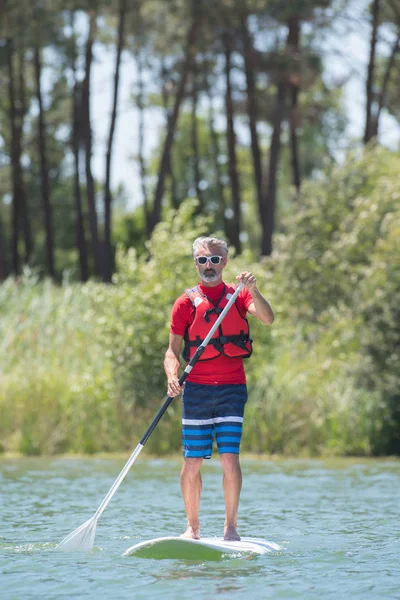 Mann genießt Fahrt auf dem See mit Paddelbrett — Stockfoto