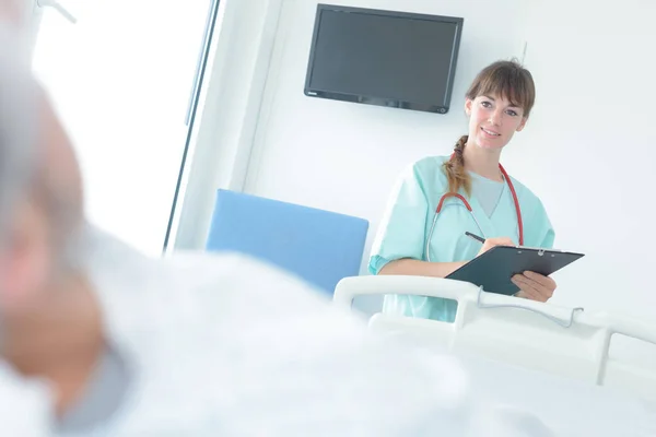 Ärztin hält Klemmbrett im Krankenhauszimmer — Stockfoto