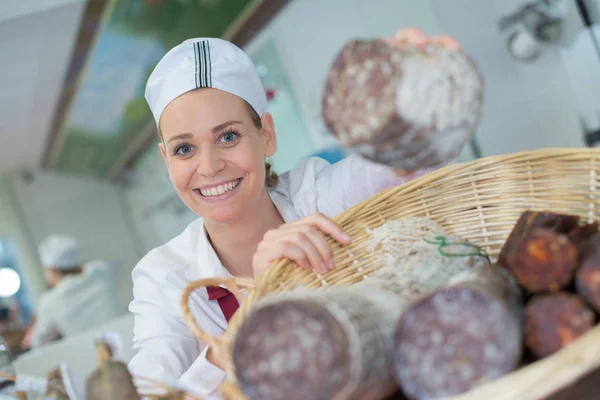 Portret van vrouwelijke verkoper het aanbieden van wursts in de lokale slagerij — Stockfoto