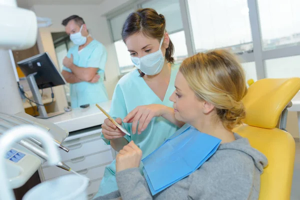 Dentista curando a una paciente en el consultorio dental — Foto de Stock