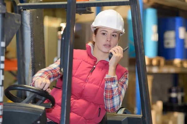 Señora hablando en walkie talkie mientras conduce la carretilla elevadora — Foto de Stock