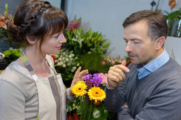 Fleuriste montrant des fleurs au client — Photo