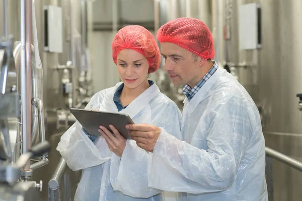 Cientista falando com seu colega segurando prancheta na fábrica — Fotografia de Stock