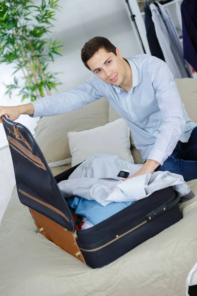 Мужчина кладет рубашку в чемодан — стоковое фото