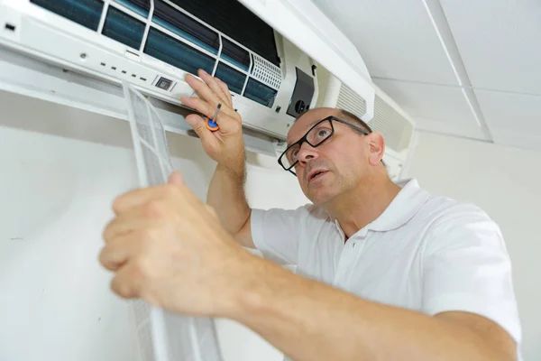 Hombre trabajando en la unidad de aire acondicionado interior —  Fotos de Stock